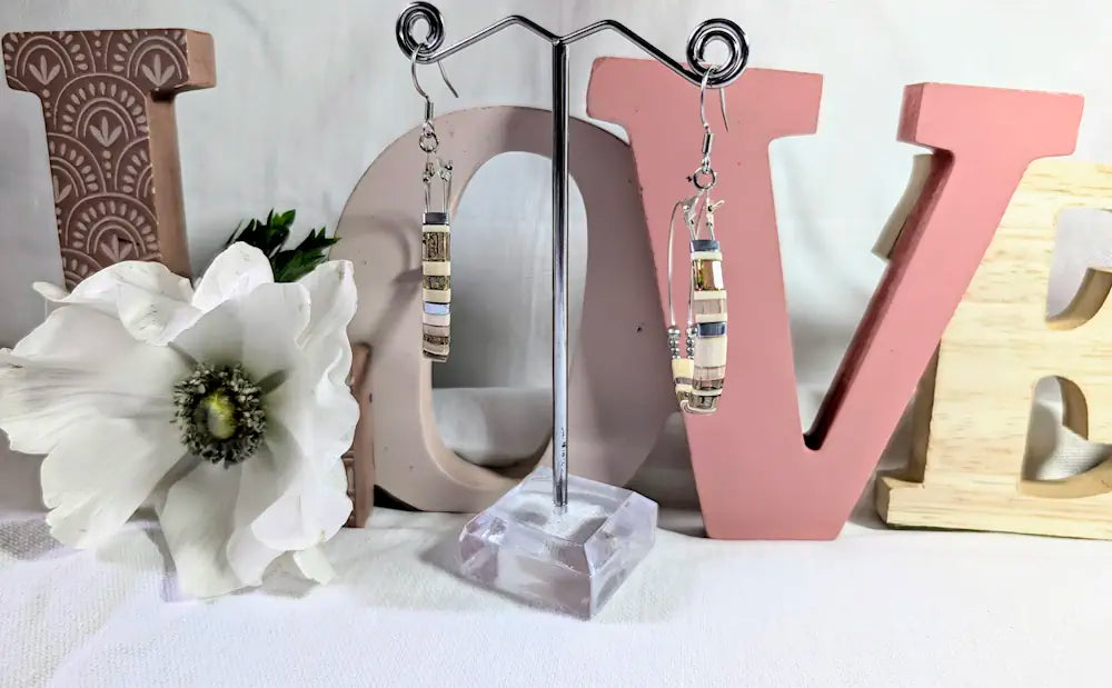 Boucles d'oreilles Perles de Rosée en acier inoxydable avec perles Miyuki Tila rose poudré, beige et taupe montées sur doubles créoles. Mise en scène fleurie.