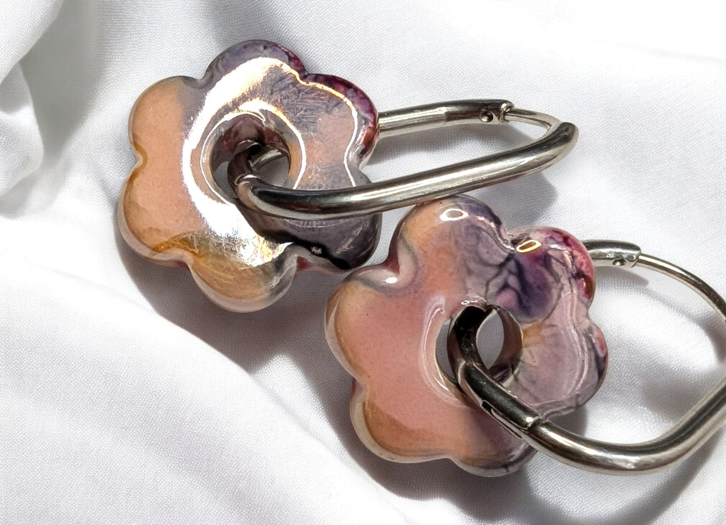Boucles d'oreilles fleur en céramique rose-noir avec créoles argentées en acier inoxydable. Un look pour toutes les occasions.
