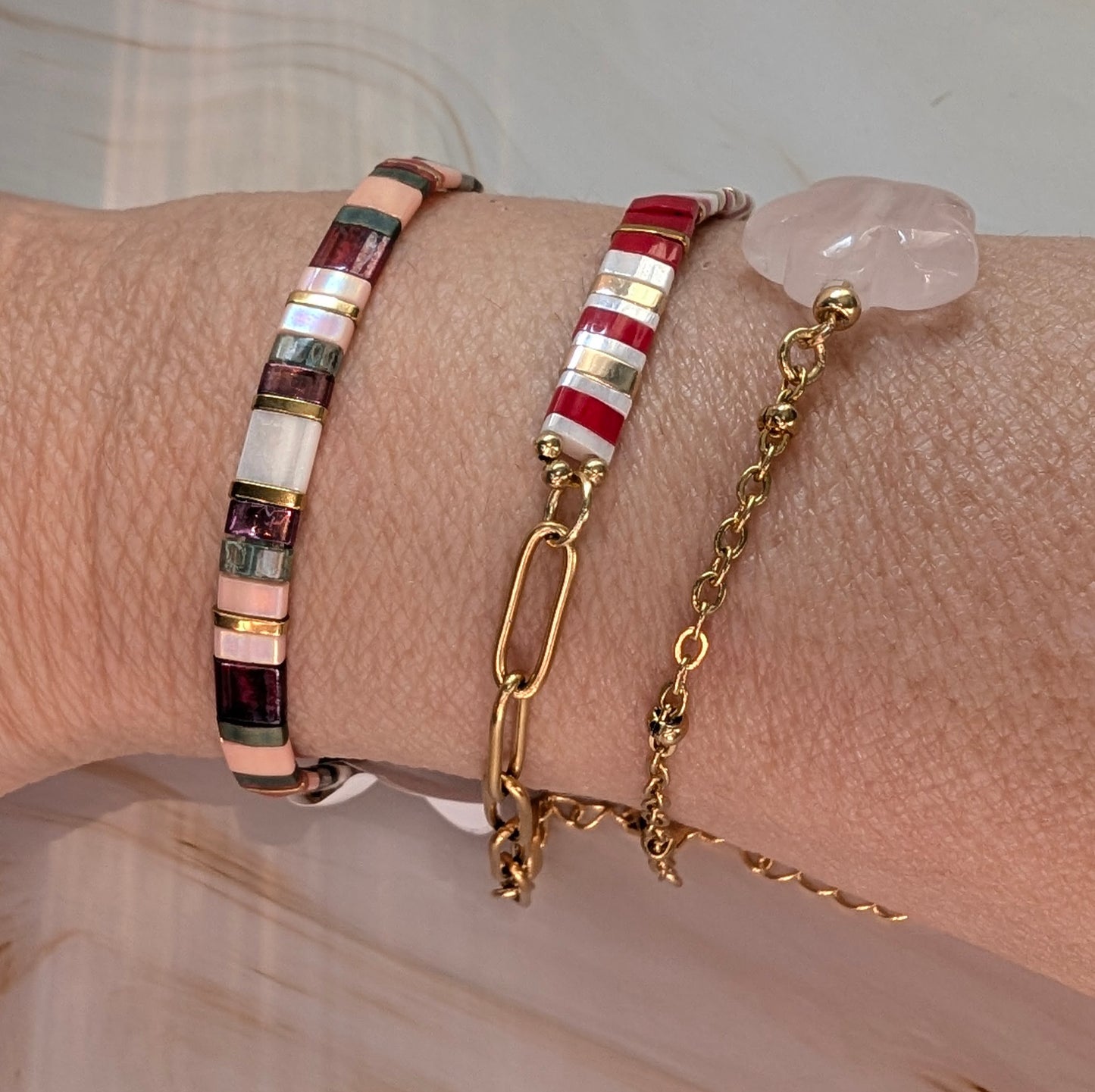 Bracelet Rosso porté au poignet, illuminant la tenue avec sa touche raffinée et colorée.Accompagné des bracelets Délia et perles de verre rosés.