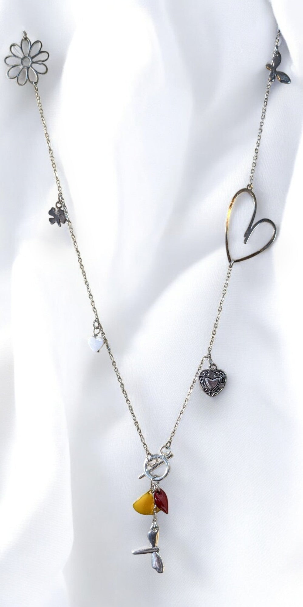 Collier sautoir Floréale en acier inoxydable argenté, orné de pampilles libellule, papillon, fleur et cœur, avec sequins émaillés jaune et rouge.