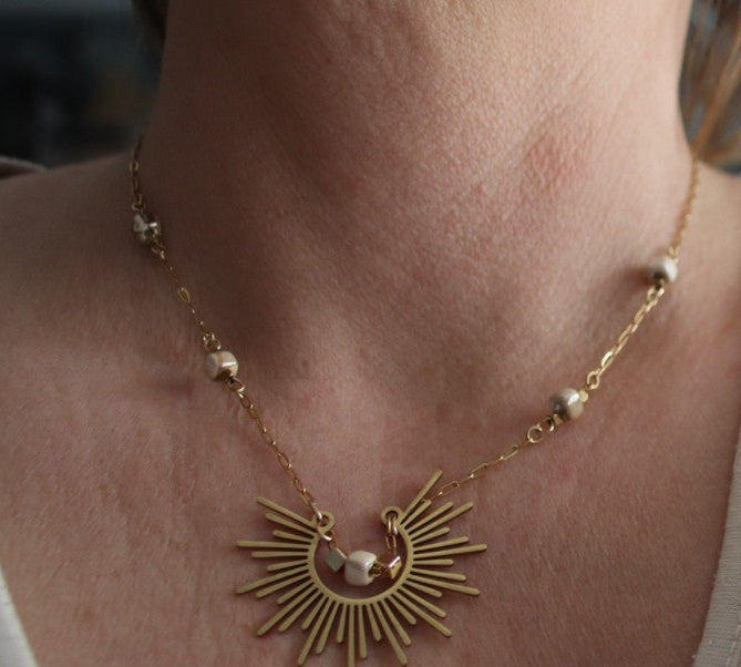 Collier Soléa en acier inoxydable doré, sublimant le décolleté avec son pendentif rayonnant et sa chaîne trombone élégante.