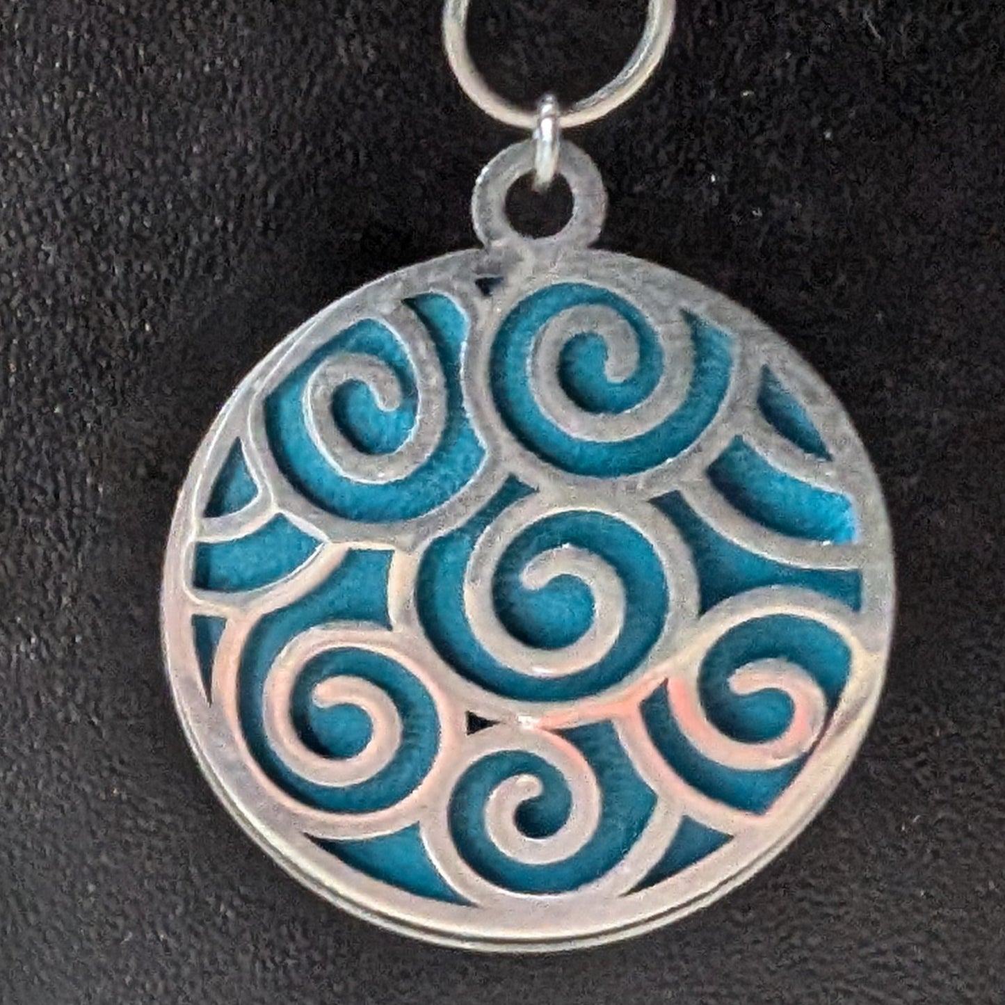 Détail des boucles d'oreilles Brise Marine en cuir et estampe, montrant les motifs vagues et l'éclat du cabochon, avec des éléments en acier inoxydable.