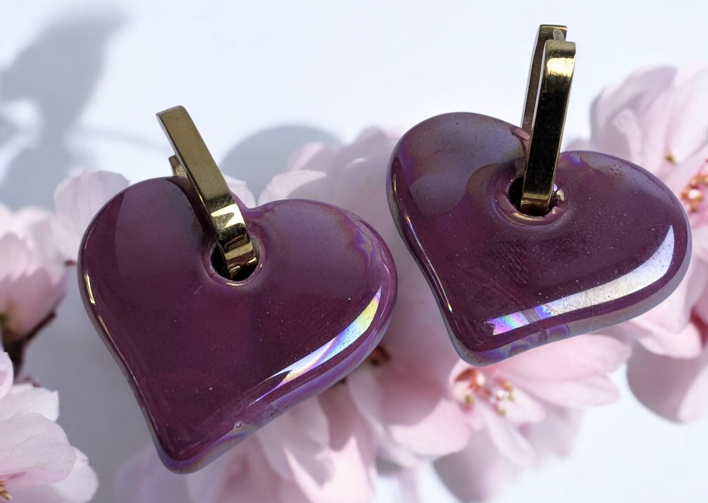 Boucles d'oreilles en céramique cœur magenta sur créole ovale dorée, design élégant et moderne.