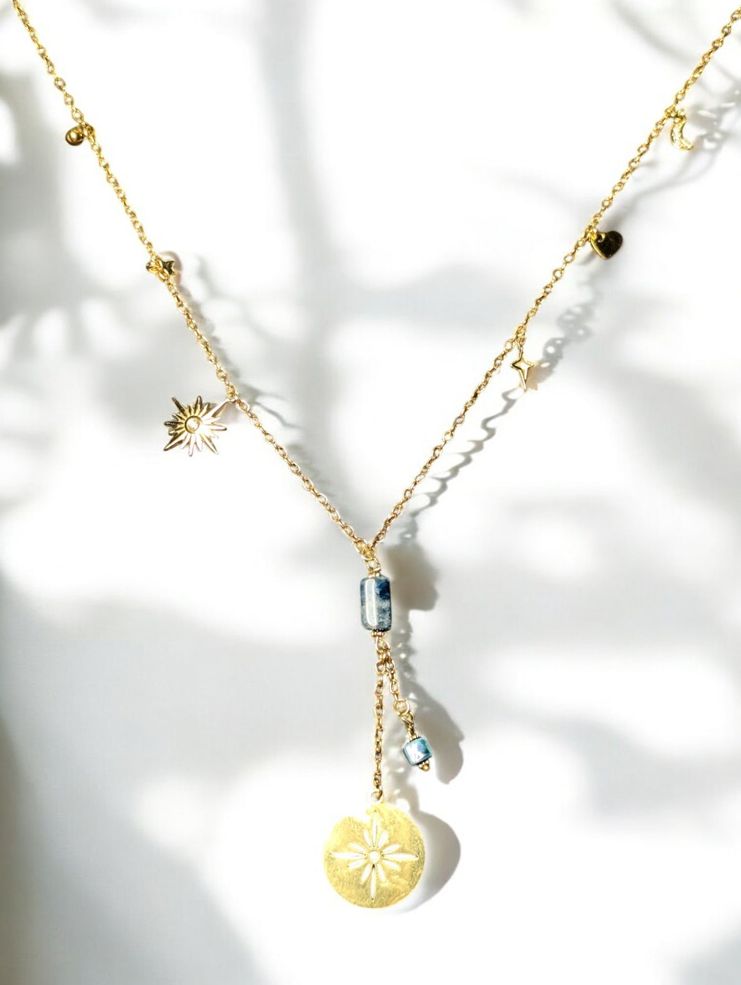 collier Constellation, mettant en valeur ses breloques célestes et sa pierre d’apatite aux reflets vibrants.