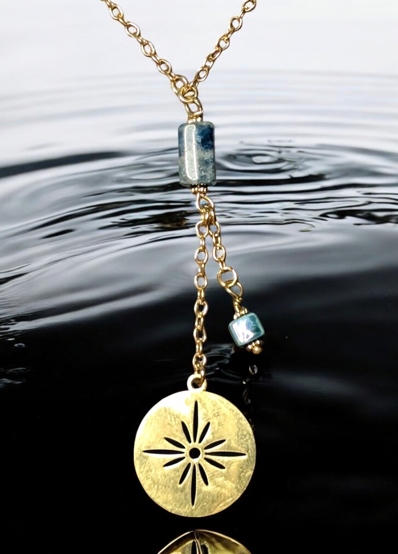 Zoom sur les détails du collier Constellation, mettant en valeur ses breloques célestes et sa pierre d’apatite aux reflets vibrants.