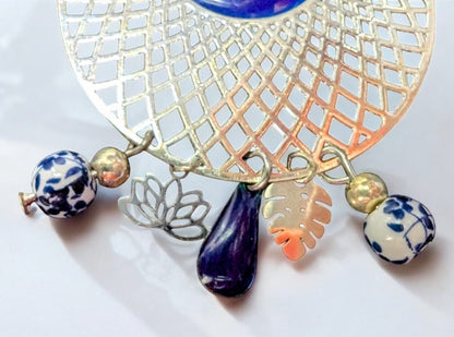 Zoom sur un Bijou raffiné : boucles pendantes Jardin d’Azur ornées de motifs floraux en céramique et de sequins émaillés bleu azur.

