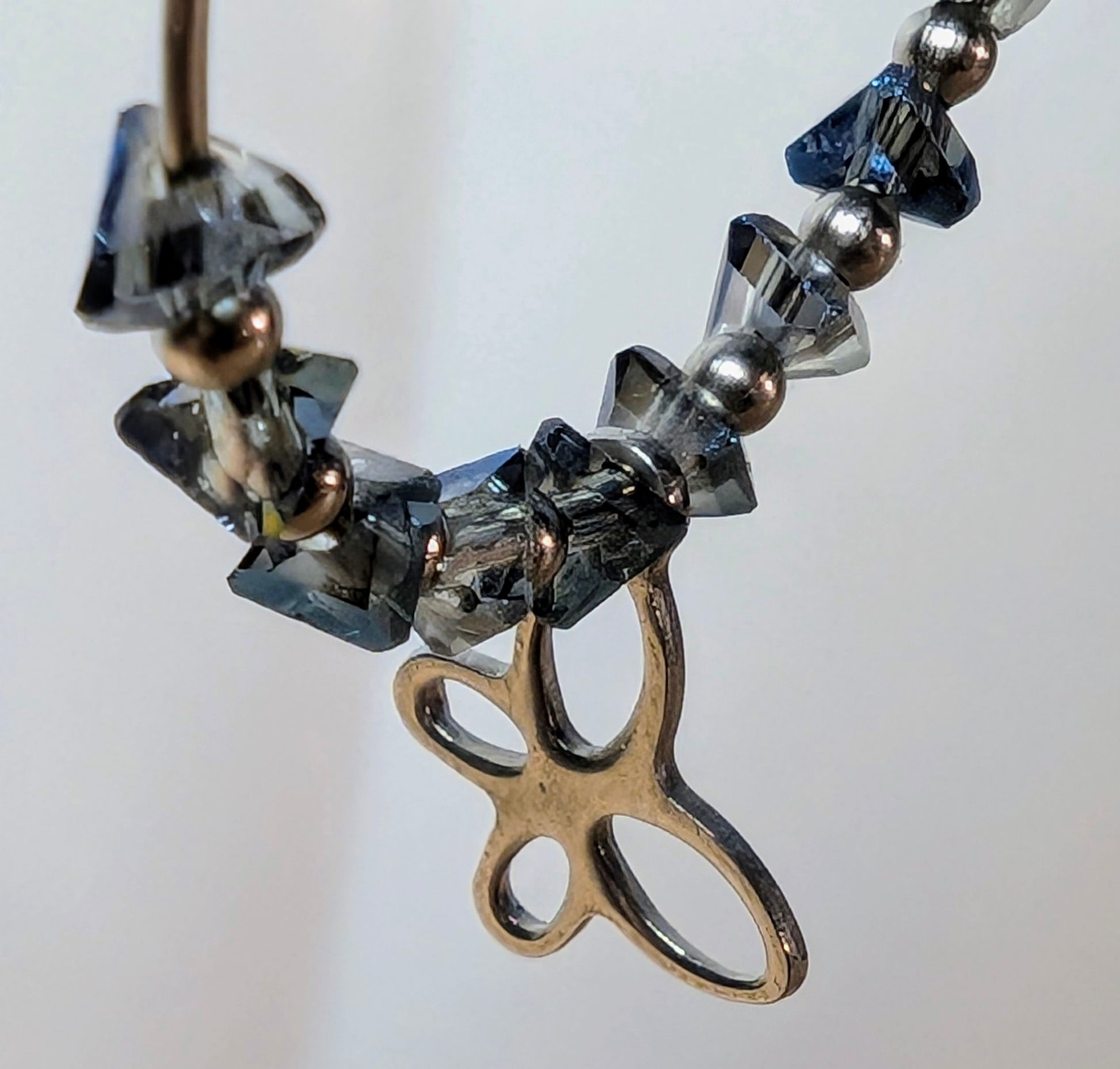 Zoom sur les éclats de verre bleu-gris et du pendentif papillon.