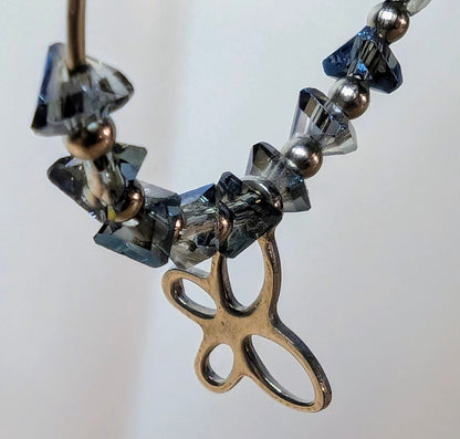 Zoom sur les éclats de verre bleu-gris et du pendentif papillon.