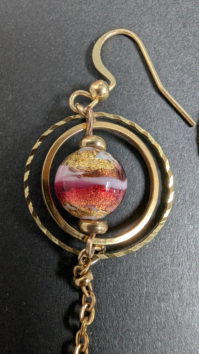 Détail des boucles d’oreilles Vénézia montrant les perles artisanales en verre de Murano rouge et rose parsemées de feuille d’or