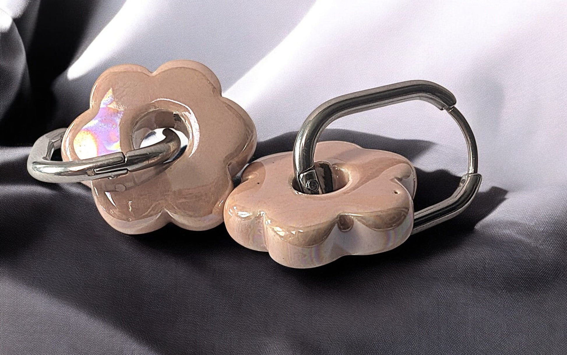 Gros plan sur une paire de boucles d’oreilles Fleur en céramique rose clair avec créoles argentées
