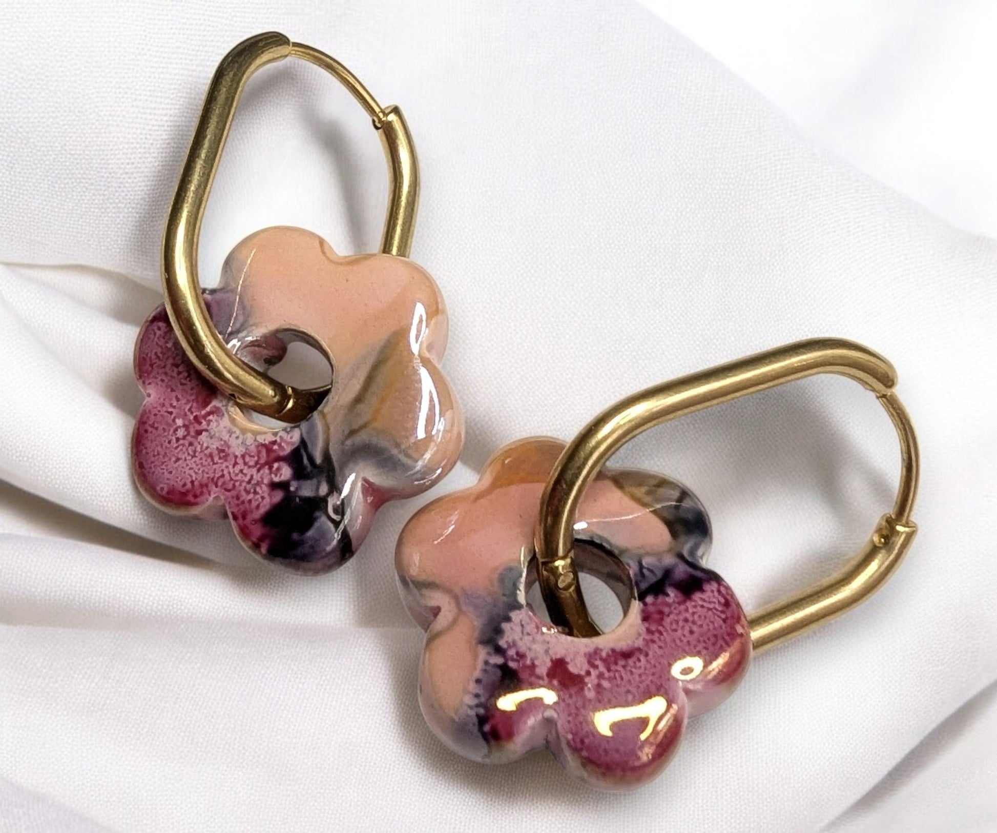Boucles d'oreilles fleur en céramique rose-noir avec créoles dorées en acier inoxydable. Un charme fou.