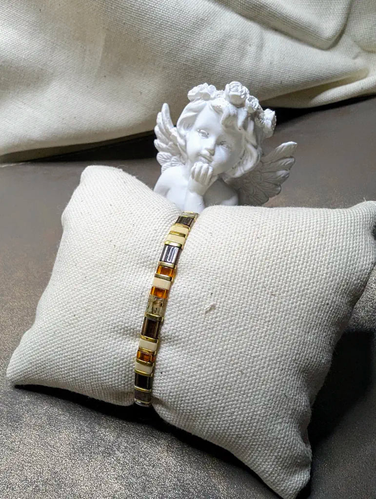 Bracelet élastiqué en perles japonaises mates et brillantes aux tons naturels. décor d'un petit angelot penseur.