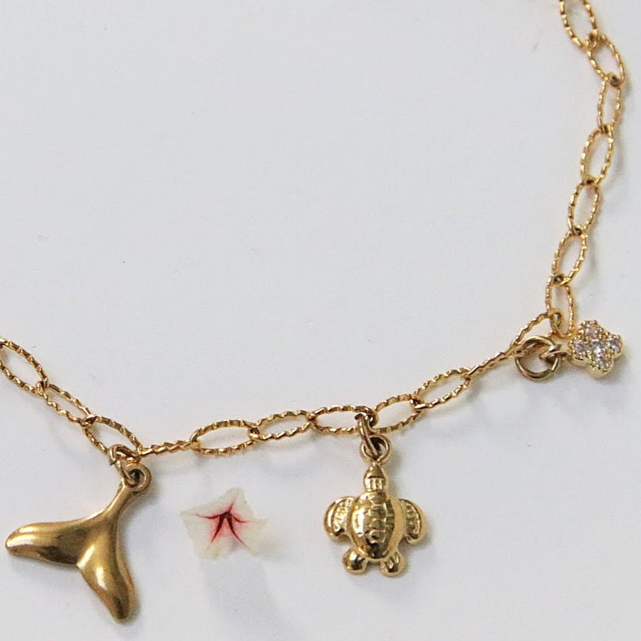 Bracelet Orély en acier inoxydable doré avec charms symboliques croix, fleur, tortue, queue de poisson et trèfle.