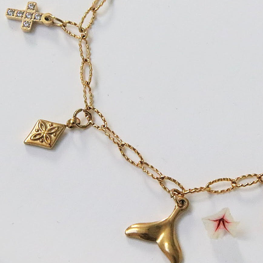 Bracelet Orély en acier inoxydable doré avec charms symboliques croix, fleur, tortue, queue de poisson et trèfle.