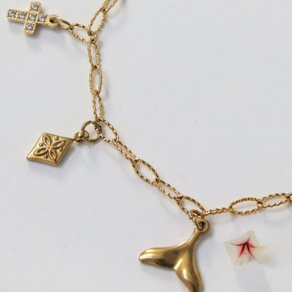 Bracelet Orély en acier inoxydable doré avec charms symboliques croix, fleur, tortue, queue de poisson et trèfle.
