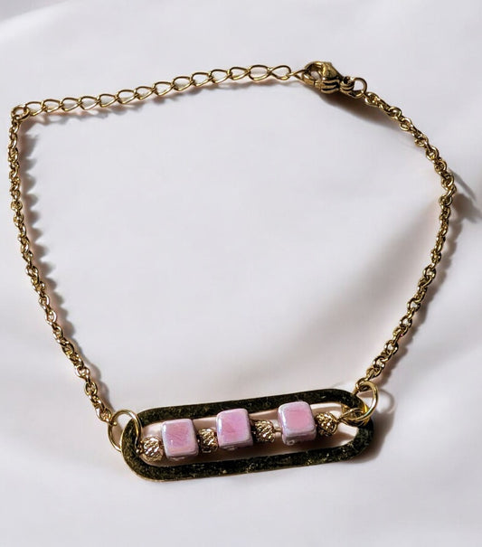 Bracelet Roséa en gros plan, mettant en valeur ses perles en céramique rose et ses détails dorés raffinés.