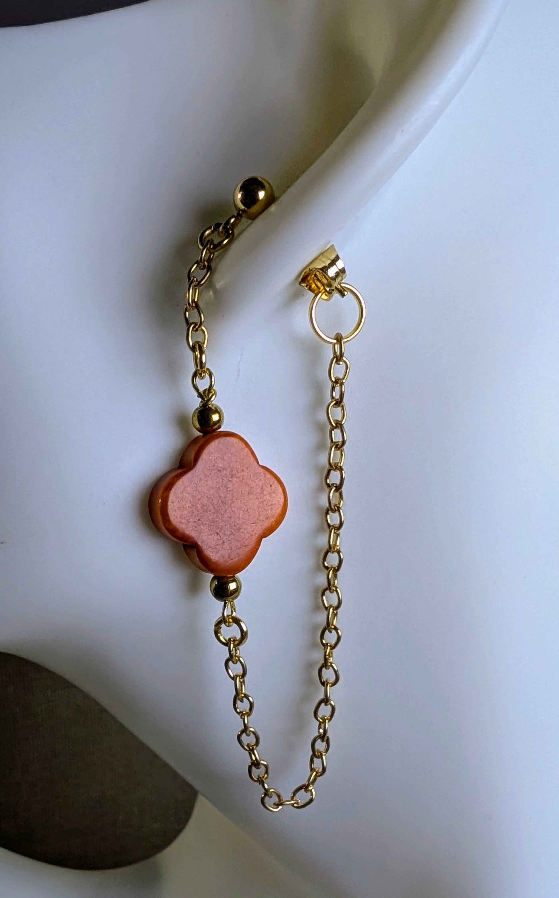 Boucles d’oreilles Cléa zoom sur le  trèfle  orange et chaine dorée.