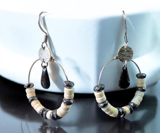 Boucles d'oreilles Céleste en acier inoxydable, avec perles d’howlite ivoire et hématite grise sur un cercle argenté.