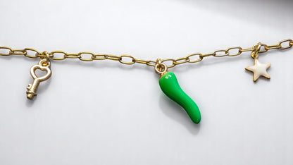 Zoom sur les pendentifs du collier Lucéa – clé, talisman piment vert, étoile blanche.