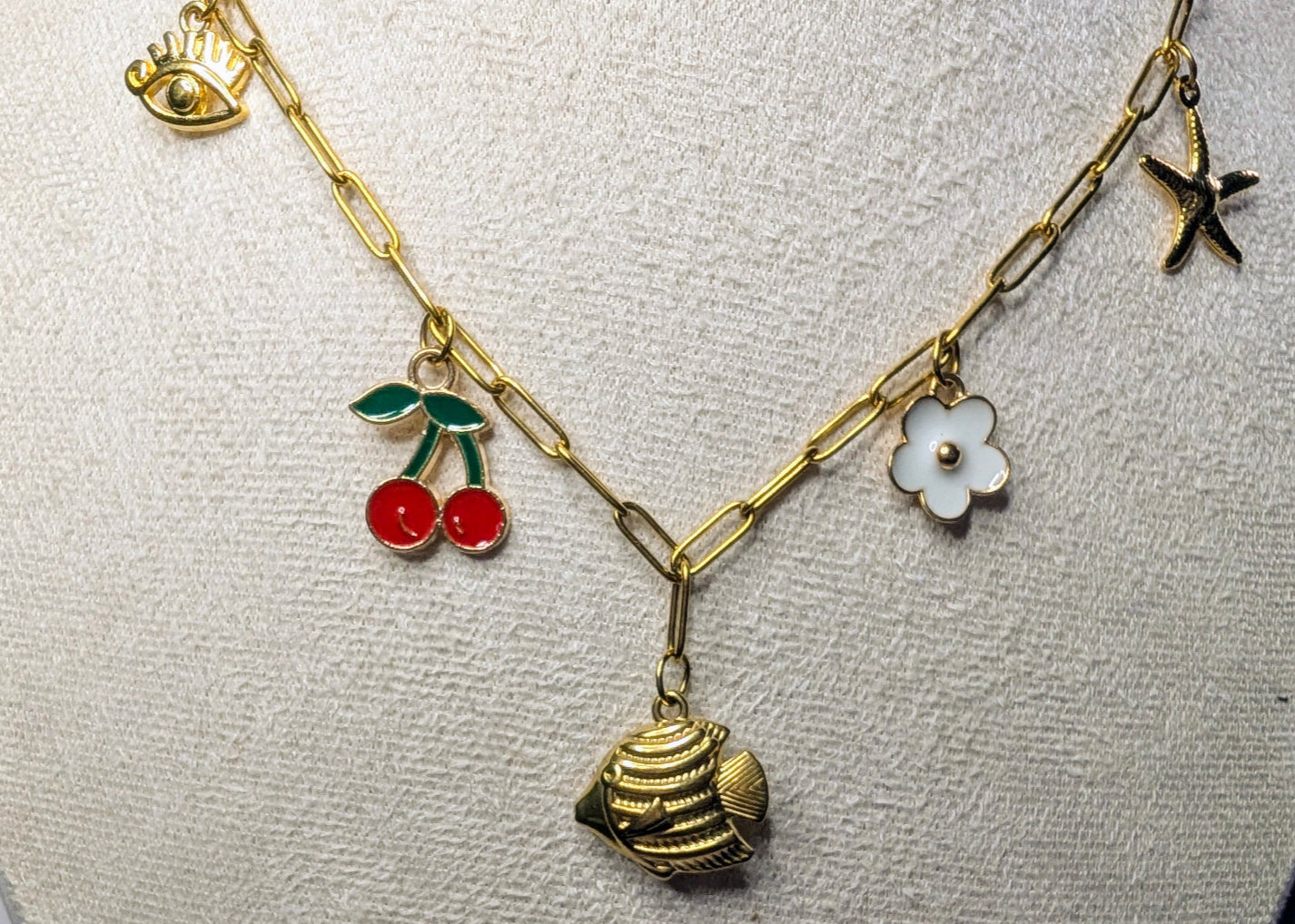 Détail du collier Zélie : œil, cerises, poisson, fleur blanche et étoile de mer