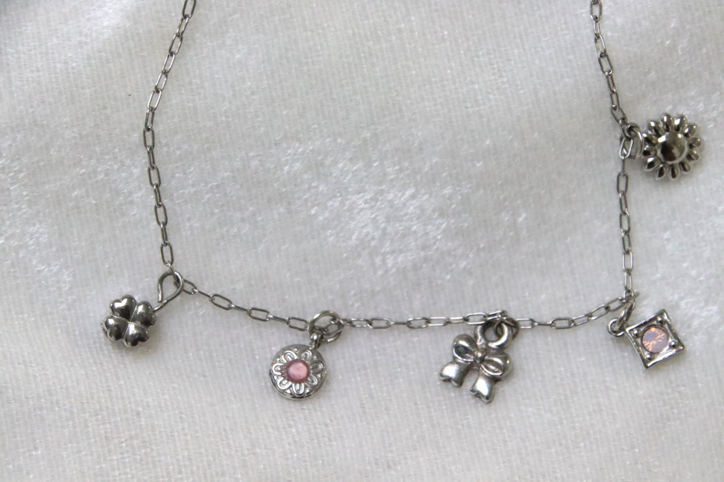 Isia : Raffiné, lumineux et féminin, le bracelet parfait pour un style élégant au quotidien. Détail des charms : trèfme, rosace rosée, petit noeud, losange rosé et petite marguerite