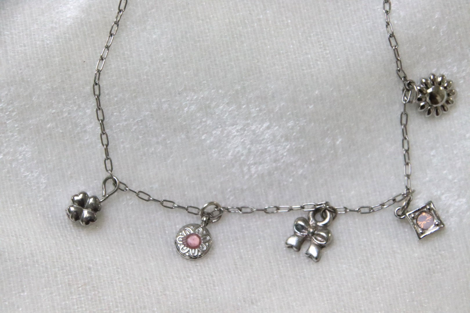 Isia : Raffiné, lumineux et féminin, le bracelet parfait pour un style élégant au quotidien. Détail des charms : trèfme, rosace rosée, petit noeud, losange rosé et petite marguerite