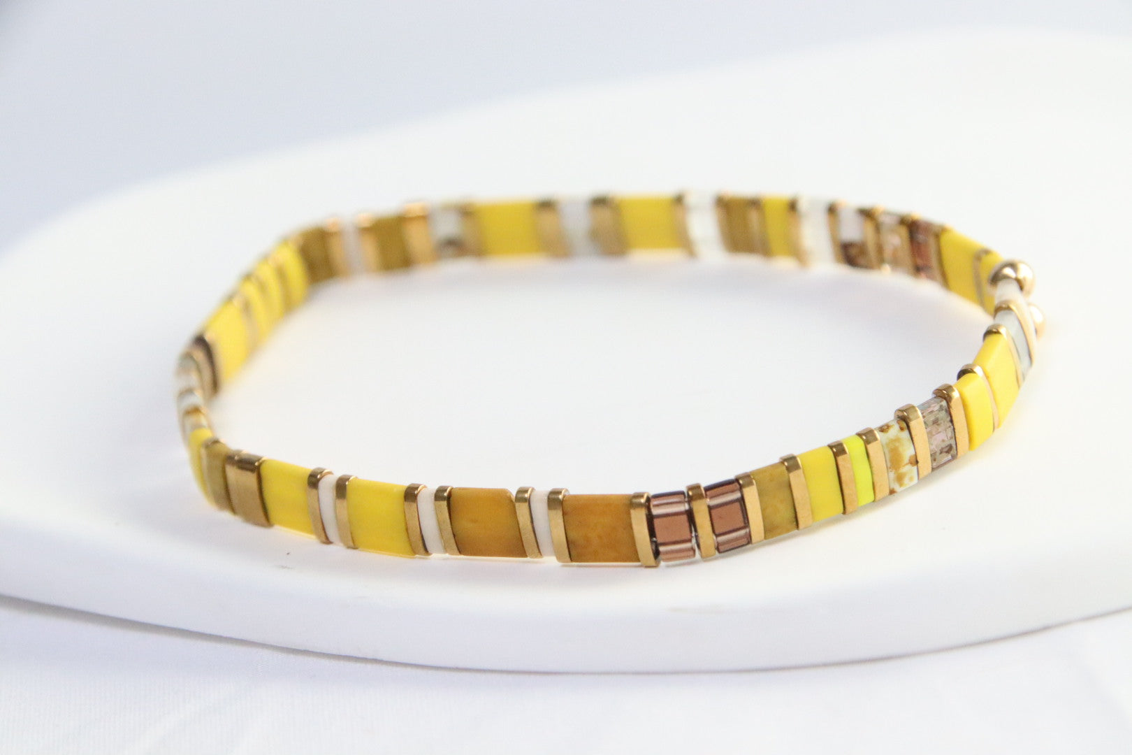 Un bracelet aux tons chauds d’automne – jaune canary mat, moutarde, brun, blanc et doré – illuminé par des perles translucides mattes pour un éclat subtil et raffiné.