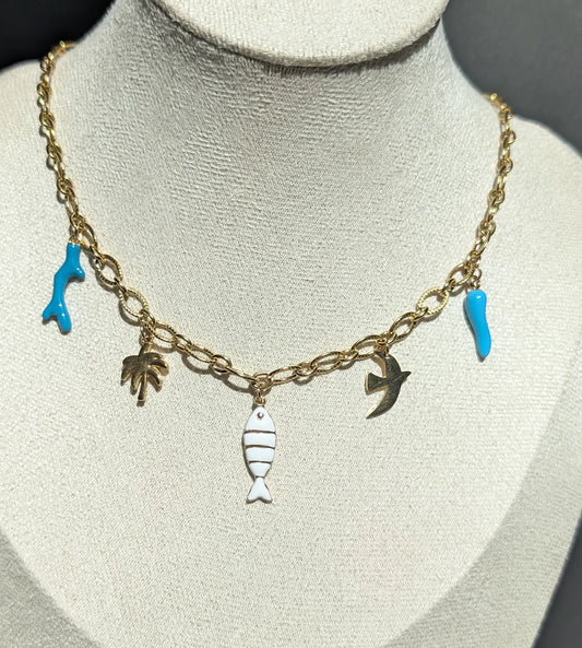 Collier Majorque avec charms tropicaux : corail turquoise, palmier doré, poisson blanc et doré, oiseau et corne d’abondance turquoise sur une chaîne ovale striée.