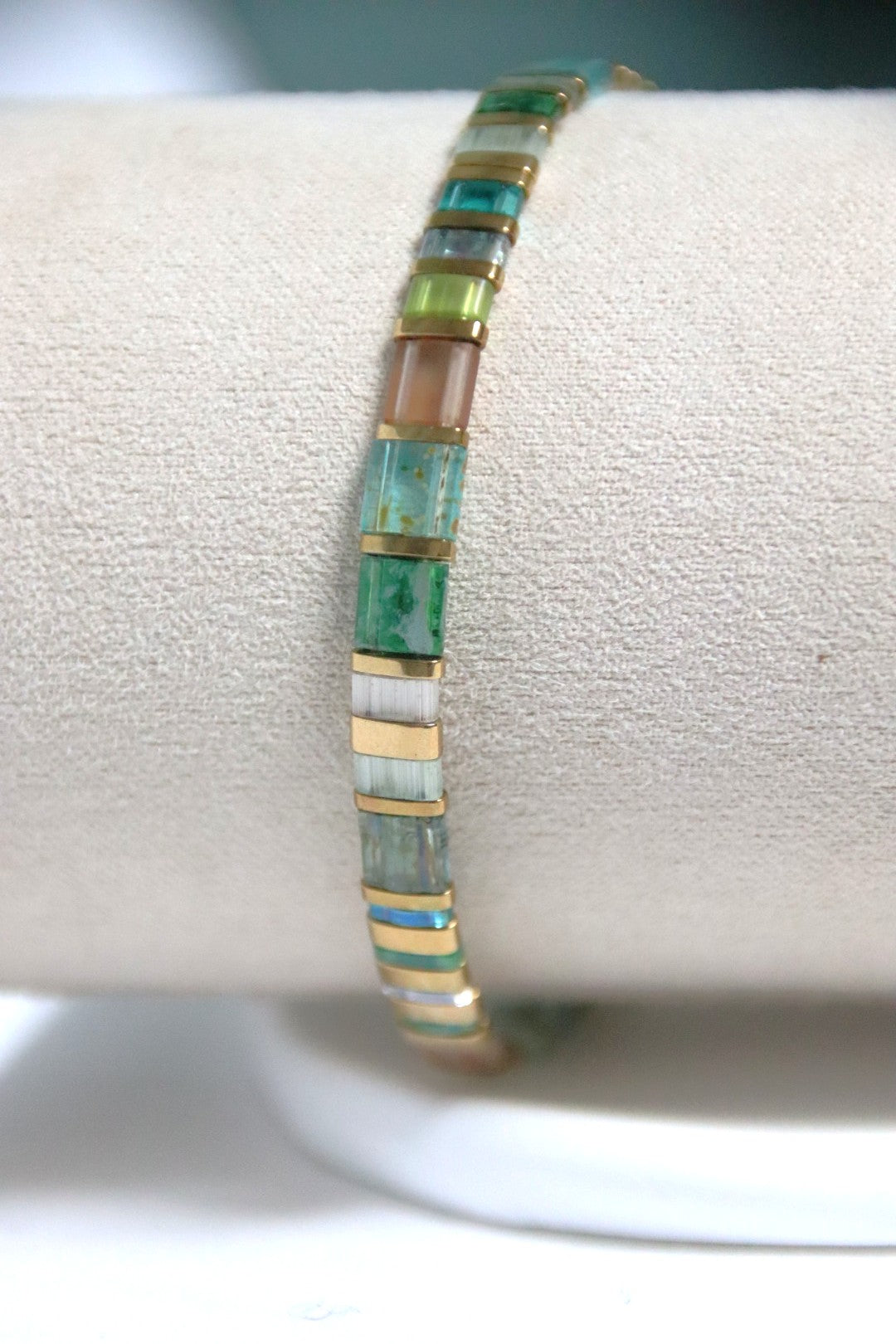 Gros plan du bracelet Sui, perles translucides jouant avec la lumière et contrastant avec l’éclat doré.
