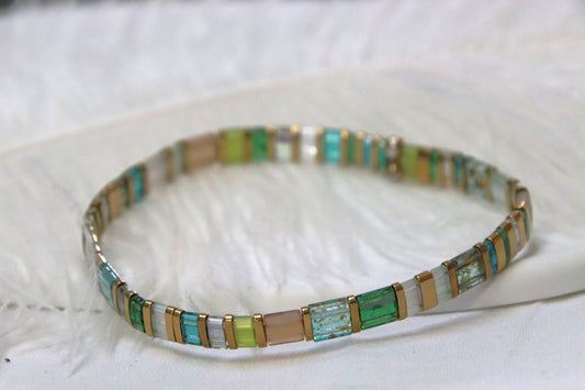 Bracelet Sui en perles transparentes bleu, vert et topaze avec touches dorées, inspiré par la pureté de l’eau.
