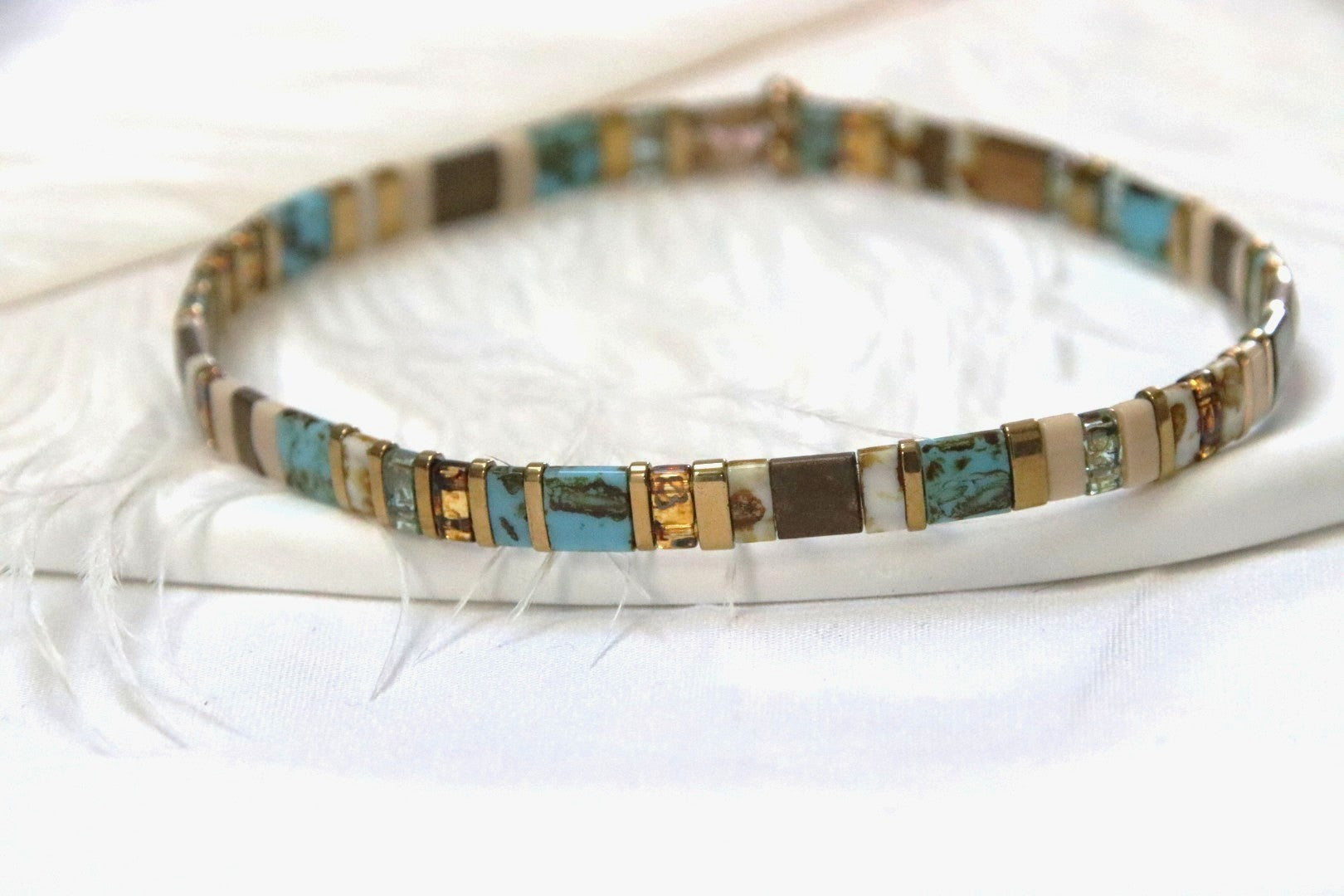 Zoom sur le bracelet Takara, mélange raffiné de perles dorées, turquoise et vertes.