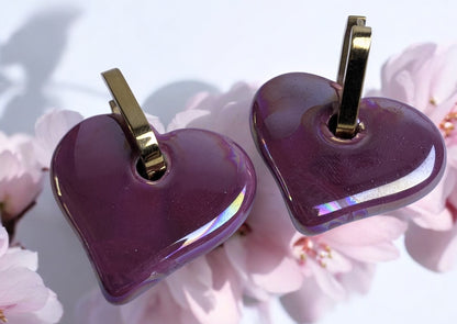 Boucles d'oreilles en céramique cœur magenta sur créole ovale dorée, design élégant et moderne.

