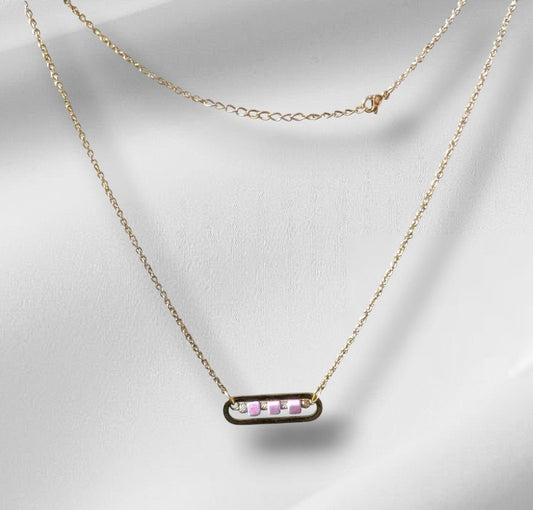Collier Roséa en acier inoxydable doré avec perles cubes en céramique rose et perles métalliques ciselées, présenté à plat