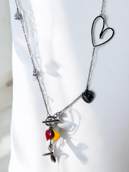 Collier sautoir Floréale en acier inoxydable argenté, orné de pampilles libellule, papillon, fleur et cœur, avec sequins émaillés jaune et rouge.